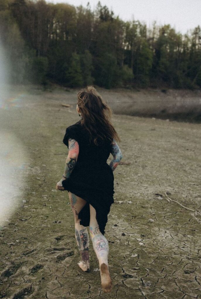 Angelina Katharina Petersen in Leipzig, im schwarzen Kleid laufend in der Natur, die Haare wehen im Wind