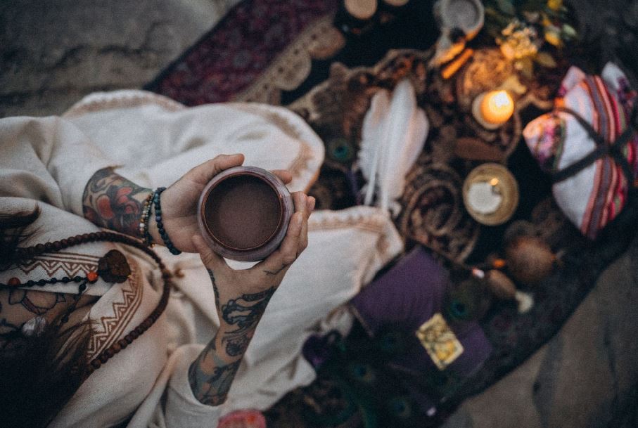 Kakao-Zeremonie in Leipzig: Hände von Angelina Katharina Petersen mit einer Kakaotasse, umgeben von Kerze, Klangschale, Blumen und zeremoniellen Gegenständen