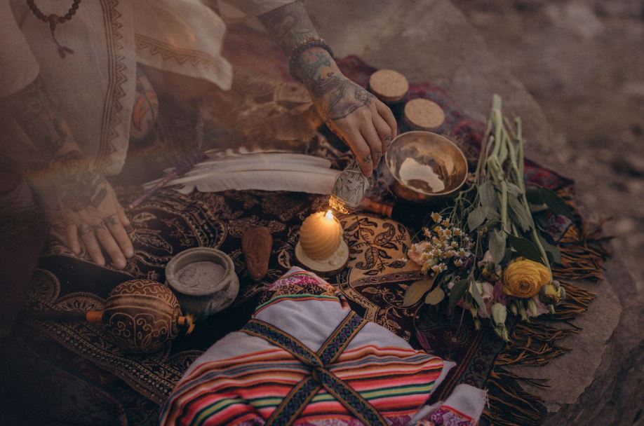 Schamanisches Ritual in Leipzig: Angelina Katharina Petersen entzündet Palo-Salbei an einer Kerze, mit Klangschale, Räucherstäbchen, Blumen-Mesa und Rassel im Freien