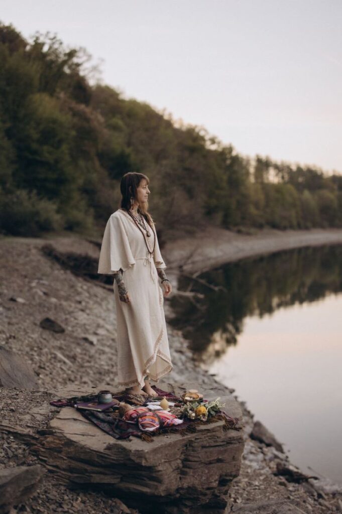 Angelina Katharina Petersen steht auf einem Felsen am Wasser, sie arbeitet als Schamanin in Deutschland