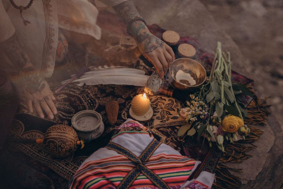 Schamanisches Ritual in Leipzig: Angelina Katharina Petersen entzündet Salbei an einer Kerze, mit Klangschale, Räucherstäbchen, Blumen-Mesa und Rassel im Freien