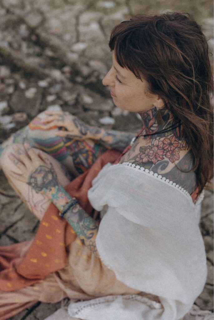 Porträt von Angelina Katharina Petersen in Leipzig, von oben fotografiert in luftiger Sommerkleidung, mit sichtbaren Tätowierungen am Hals, Nacken und Dekolleté