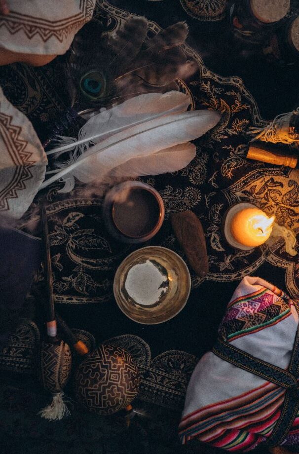 Zeremonielle Gegenstände einer Schamanischen Kakaozeremonie mit Federn, einer Klangschale, Kerze und ornamenten Mustern